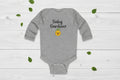 Gray baby onesie with 'Baby Gardener' text and emoji on a white background