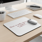 Desk setup with a mouse pad, keyboard, mouse, and mug on a wooden desk.