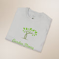 Folded gray t-shirt with green tree and 'Garden Strong' text on a beige background