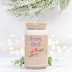 Glass jar with straw and 'Grow, Girl!' text and floral designs on a light background