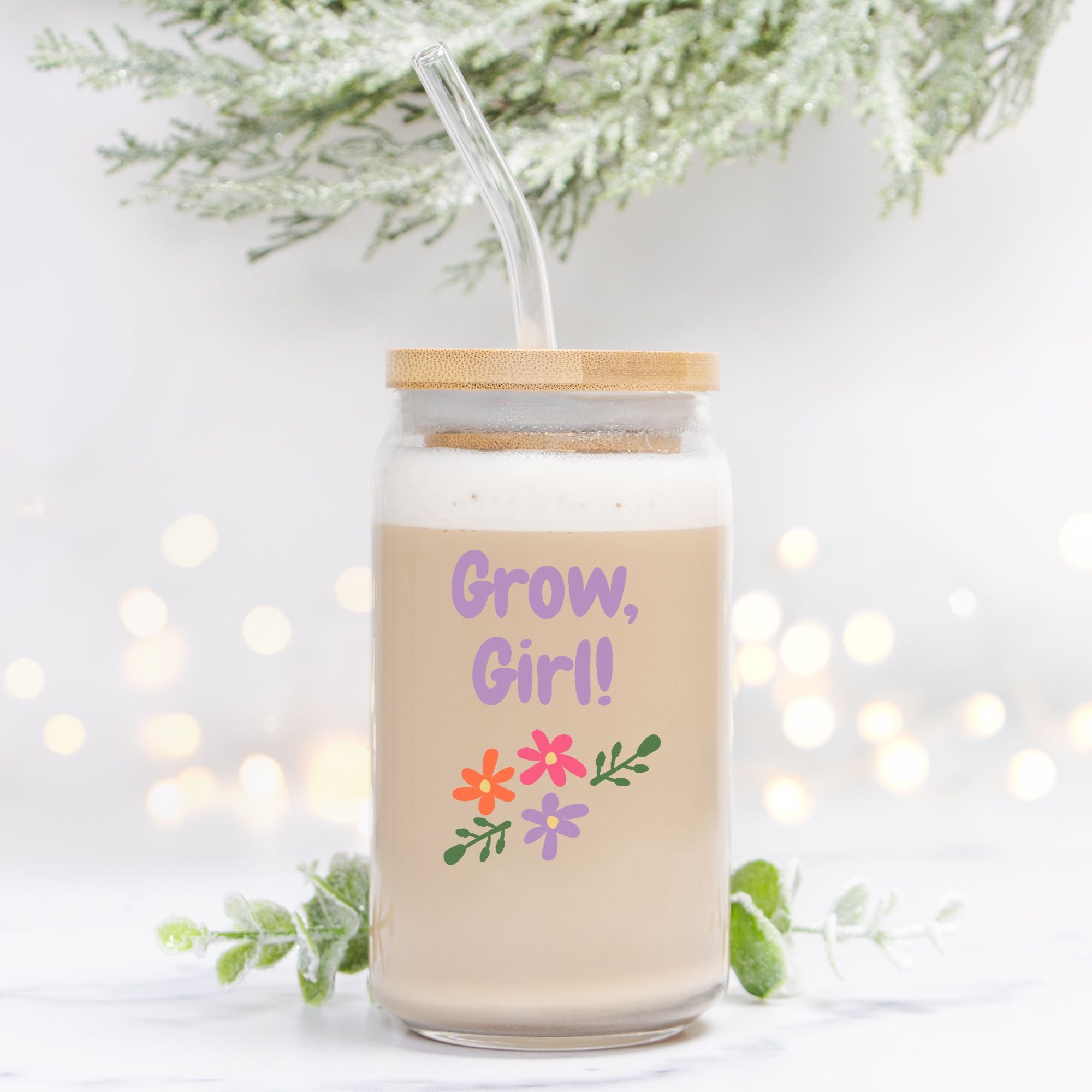 Glass jar with straw and 'Grow, Girl!' text and floral designs on a light background