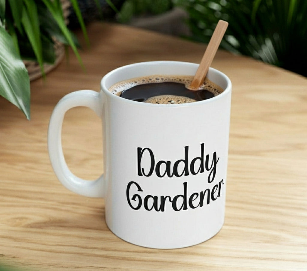 White mug with 'Daddy Gardener' text on a wooden table with coffee and a spoon.