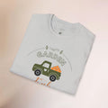 Folded light blue t-shirt with a graphic of a green truck and 'Garden' text on a beige background