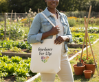 Person holding a tote bag with 'Gardener For Life' text in a garden setting