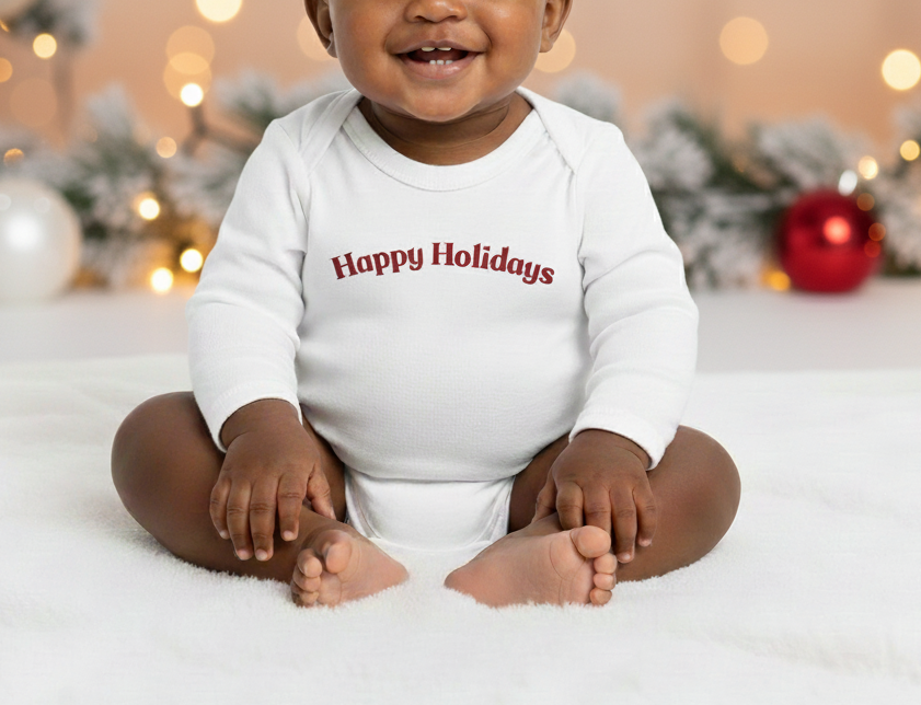 Baby wearing a 'Happy Holidays' onesie in front of Christmas decorations