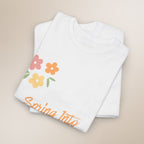 White shirt with colorful floral design and 'Spring Into' text on a beige background