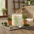 Candle labeled 'Garden Joy' on a wooden table with plants and decor.
