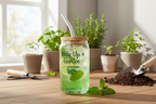 Green drink in a jar with a straw, surrounded by plants on a wooden surface.