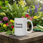 White mug with 'Mommy Gardener' text on a wooden table with flowers in the background