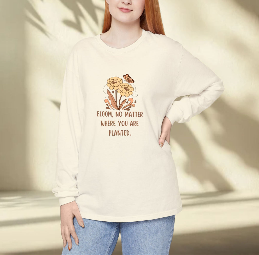 Person wearing a cream-colored sweatshirt with a floral design and text, standing against a neutral background.
