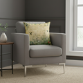 Gray armchair with a decorative pillow in a room with a window and side table.