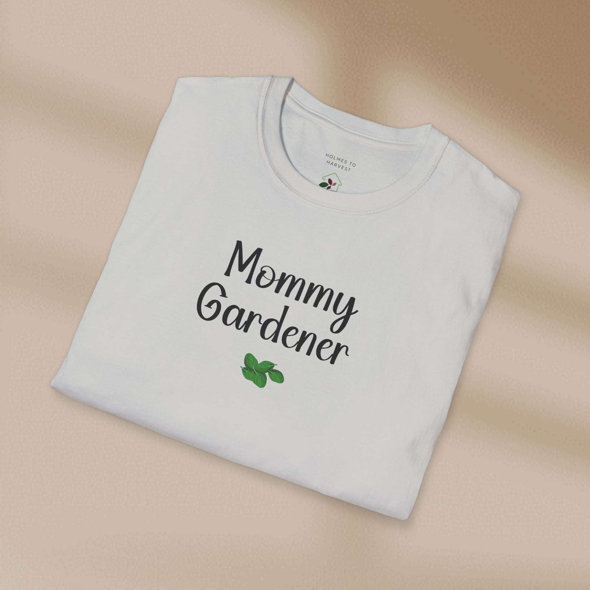 Folded white t-shirt with 'Mommy Gardener' text on a beige background