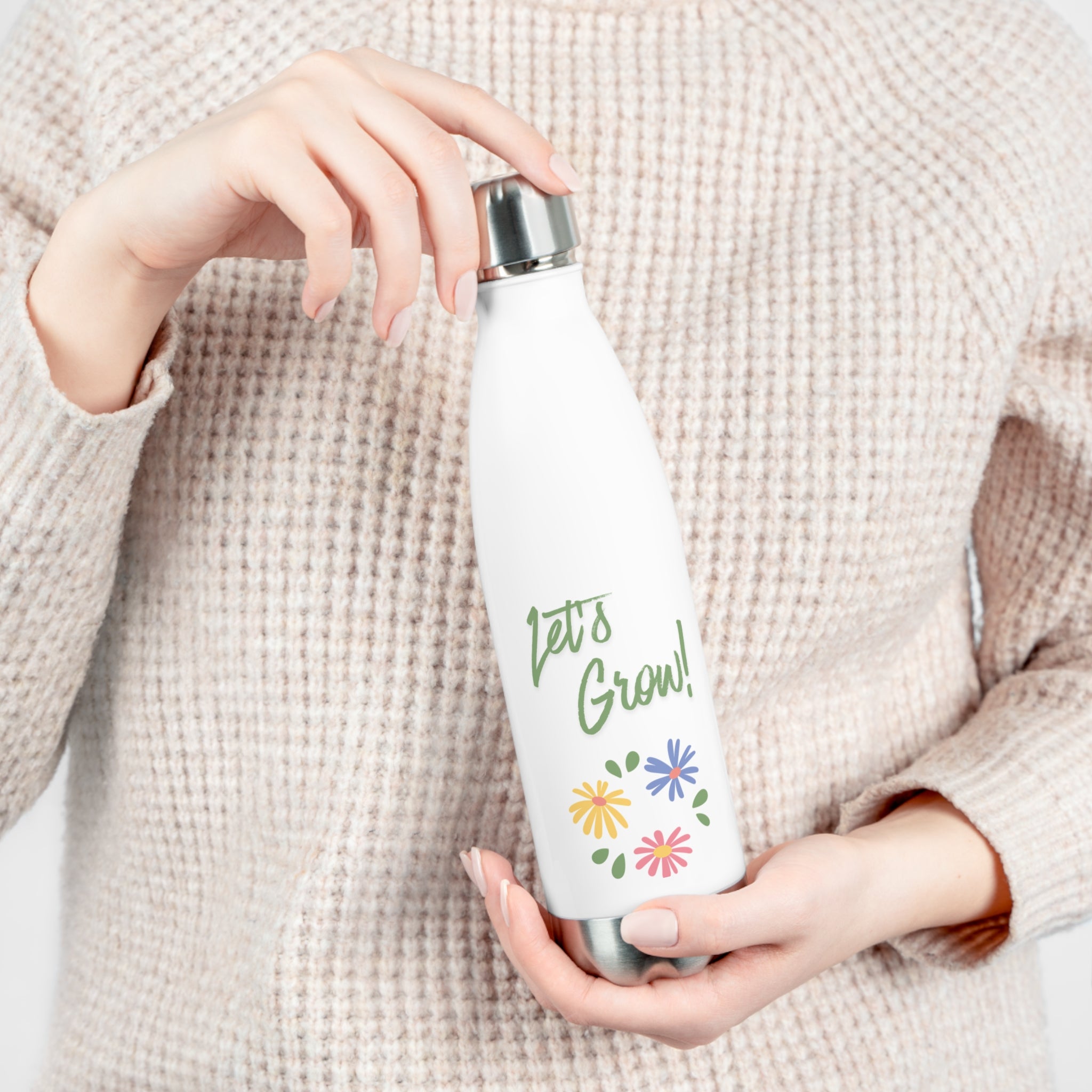Person holding a white water bottle with 'Let's Grow!' text and floral designs.