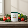 White mug with green handle on a wooden table surrounded by vegetables