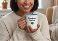 Person holding a mug with 'Grandma Gardener' text, smiling indoors.