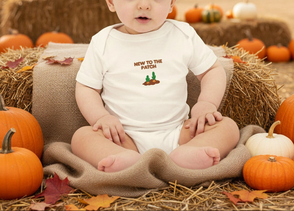 Baby wearing a white onesie with 'New to the Patch' text and cactus graphic on a beige background
