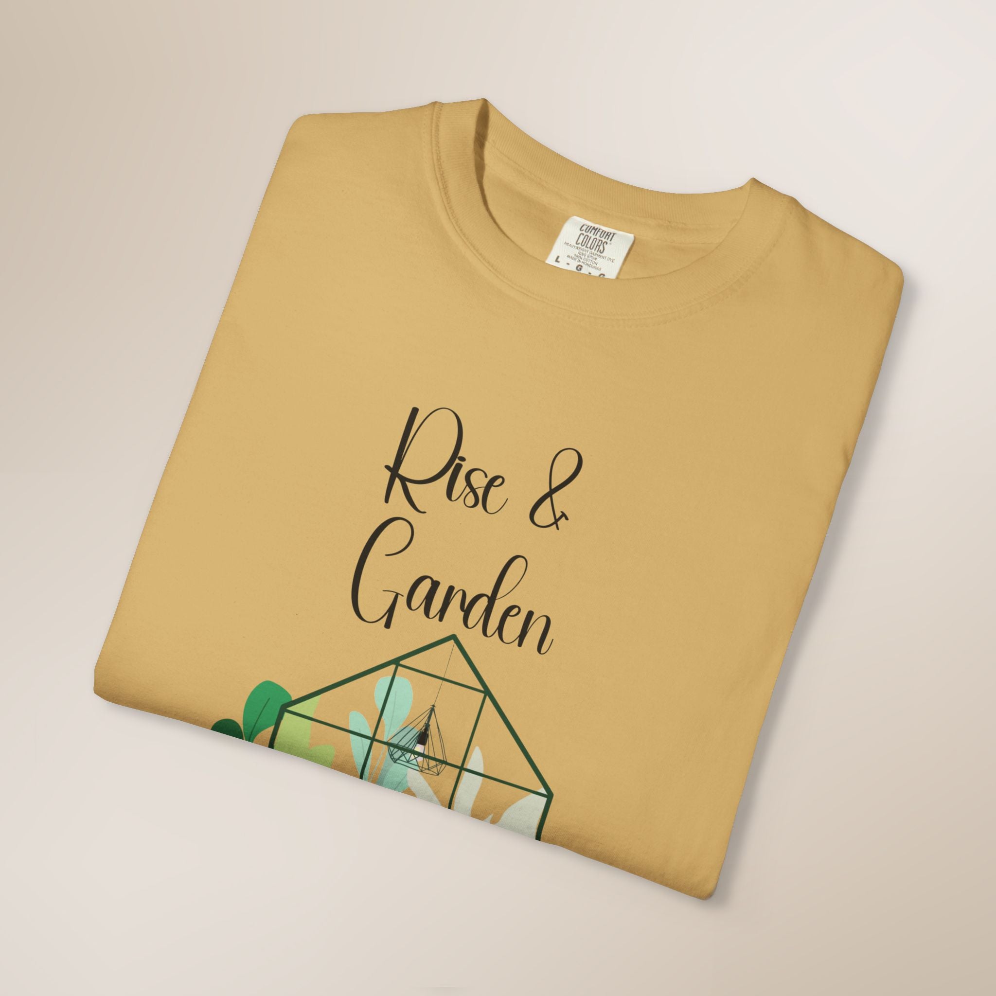 Folded mustard yellow t-shirt with 'Rise & Garden' text and green graphic on a beige background