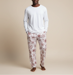 Man wearing a white long-sleeve shirt and floral pajama pants on a beige background