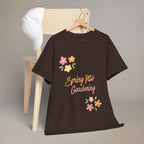 Black t-shirt with 'Spring Into Gardening' text and floral designs on a wooden chair.