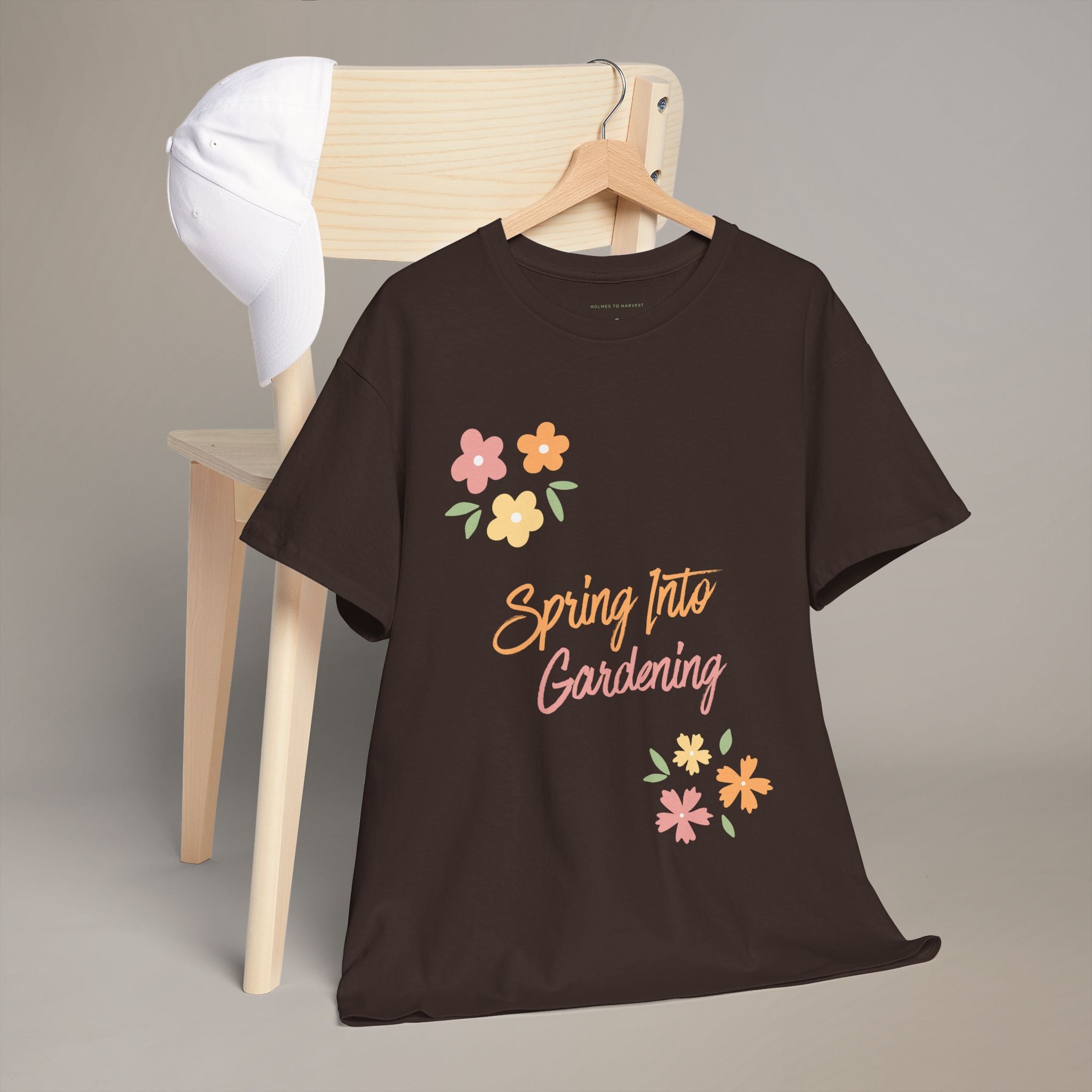 Black t-shirt with 'Spring Into Gardening' text and floral designs on a wooden chair.