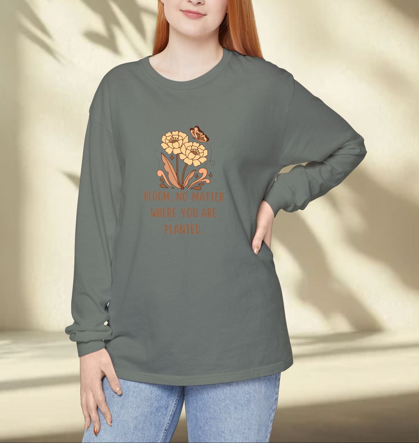 Woman wearing a green long-sleeve shirt with a floral design and text, standing against a neutral background.
