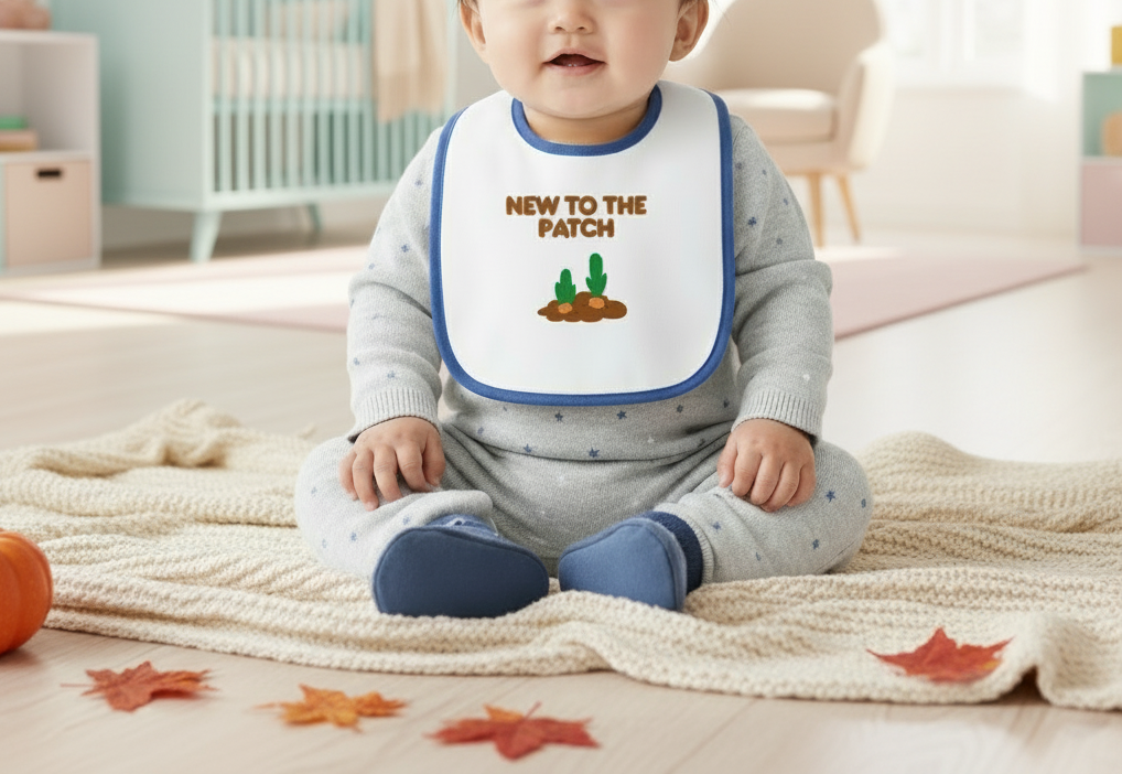 Baby wearing a bib with 'New to the Patch' text and cactus illustration, sitting on a blanket.