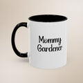 White mug with black handle and text 'Mommy Gardener' on a beige background