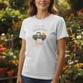 Person wearing a white t-shirt with a garden-themed design in a garden setting