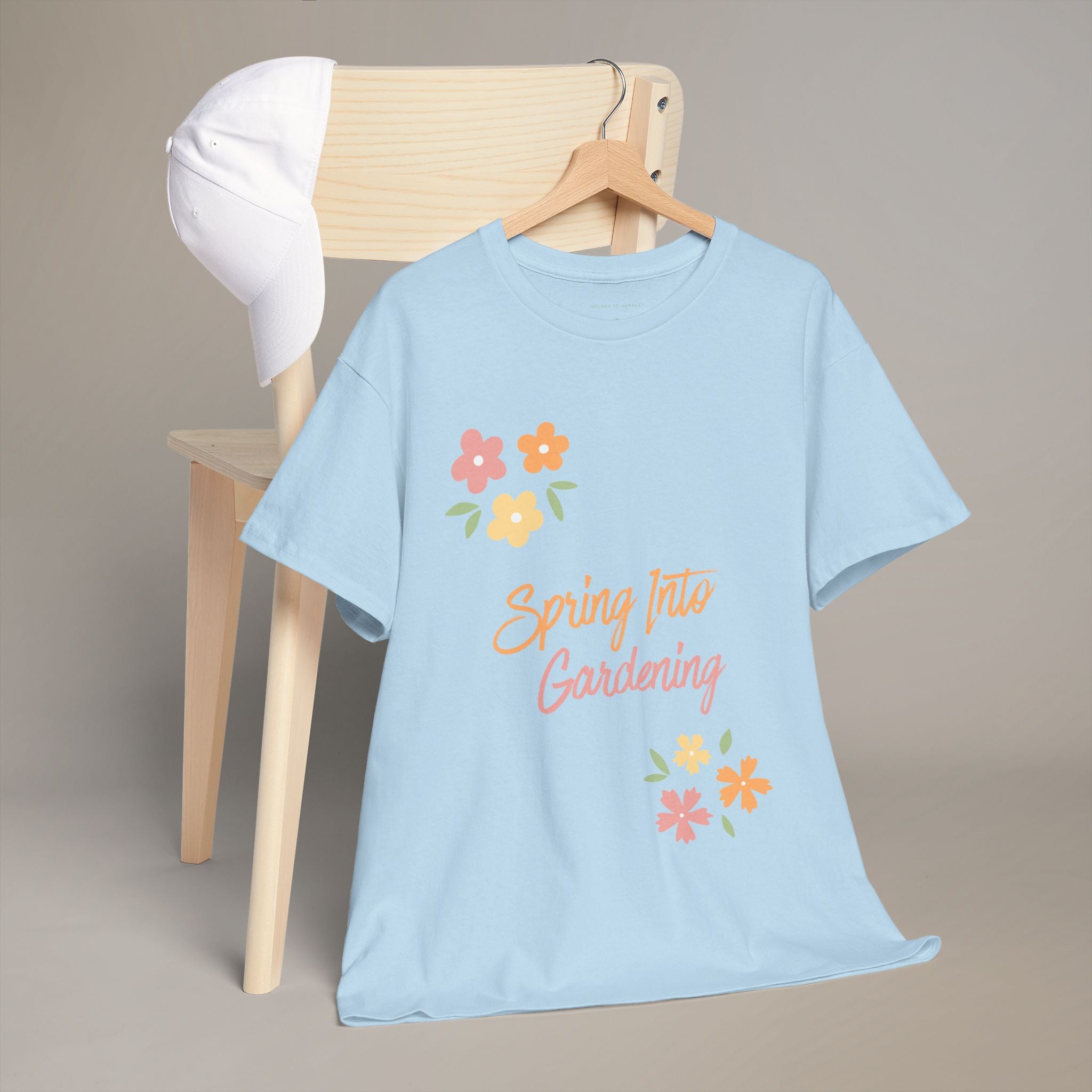 Light blue t-shirt with 'Spring Fling Gardening' text and floral designs on a hanger against a beige background.