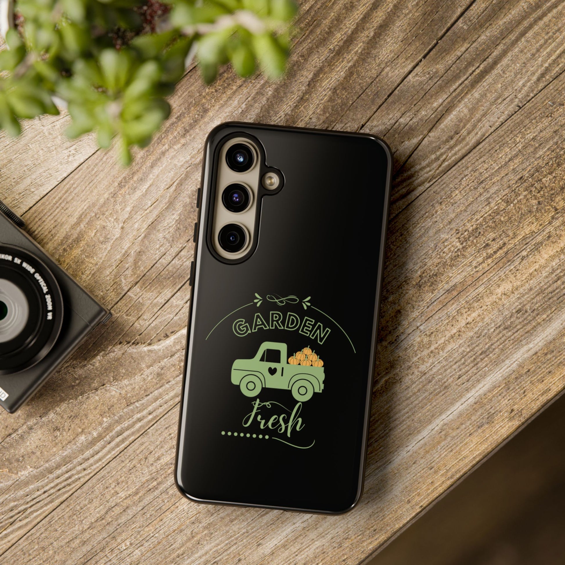 Black phone case with green truck design on a wooden surface