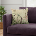 Floral-patterned pillow on a purple sofa with a plant in the background
