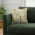 Floral-patterned pillow on a green sofa with a plant in the background