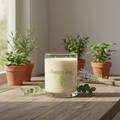 Candle labeled 'Garden Joy' on a wooden surface with potted plants in the background