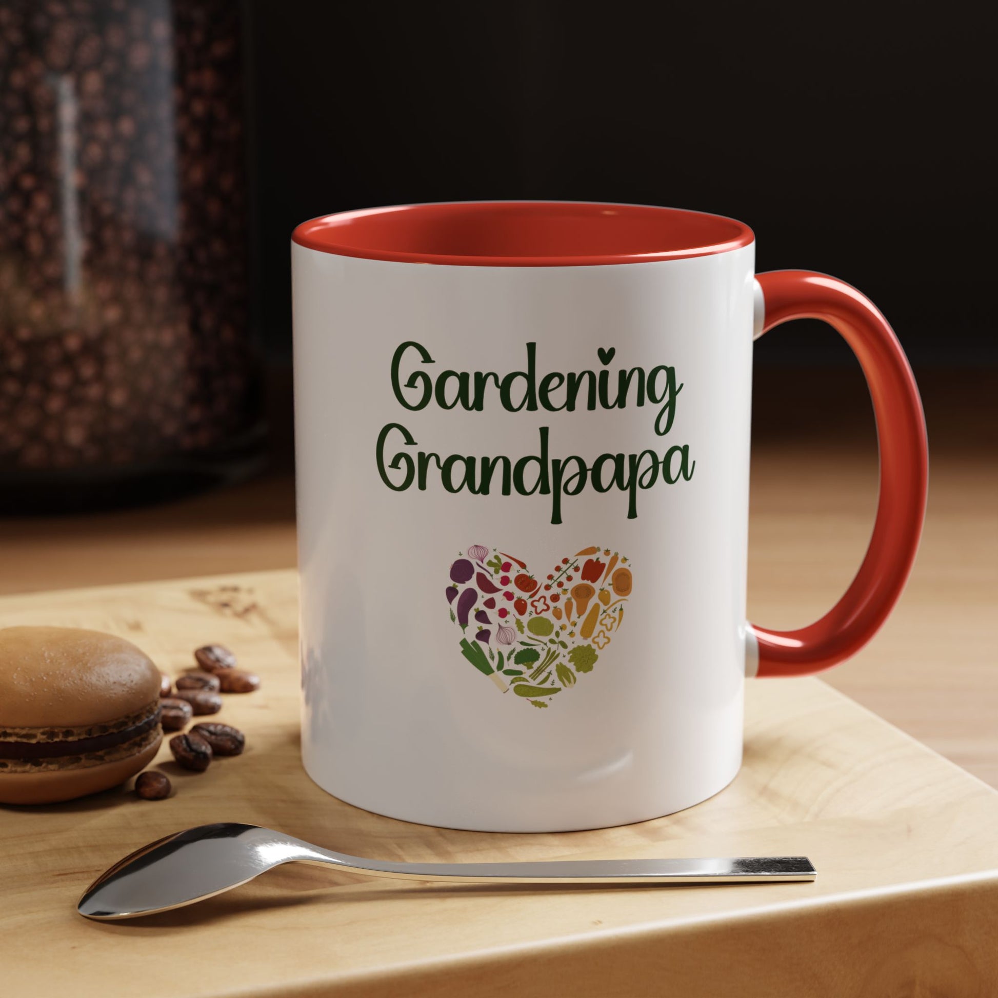 White mug with red interior and handle, featuring 'Gardening Grandpapa' text and a heart-shaped leaf design on a wooden surface with coffee beans and a spoon.