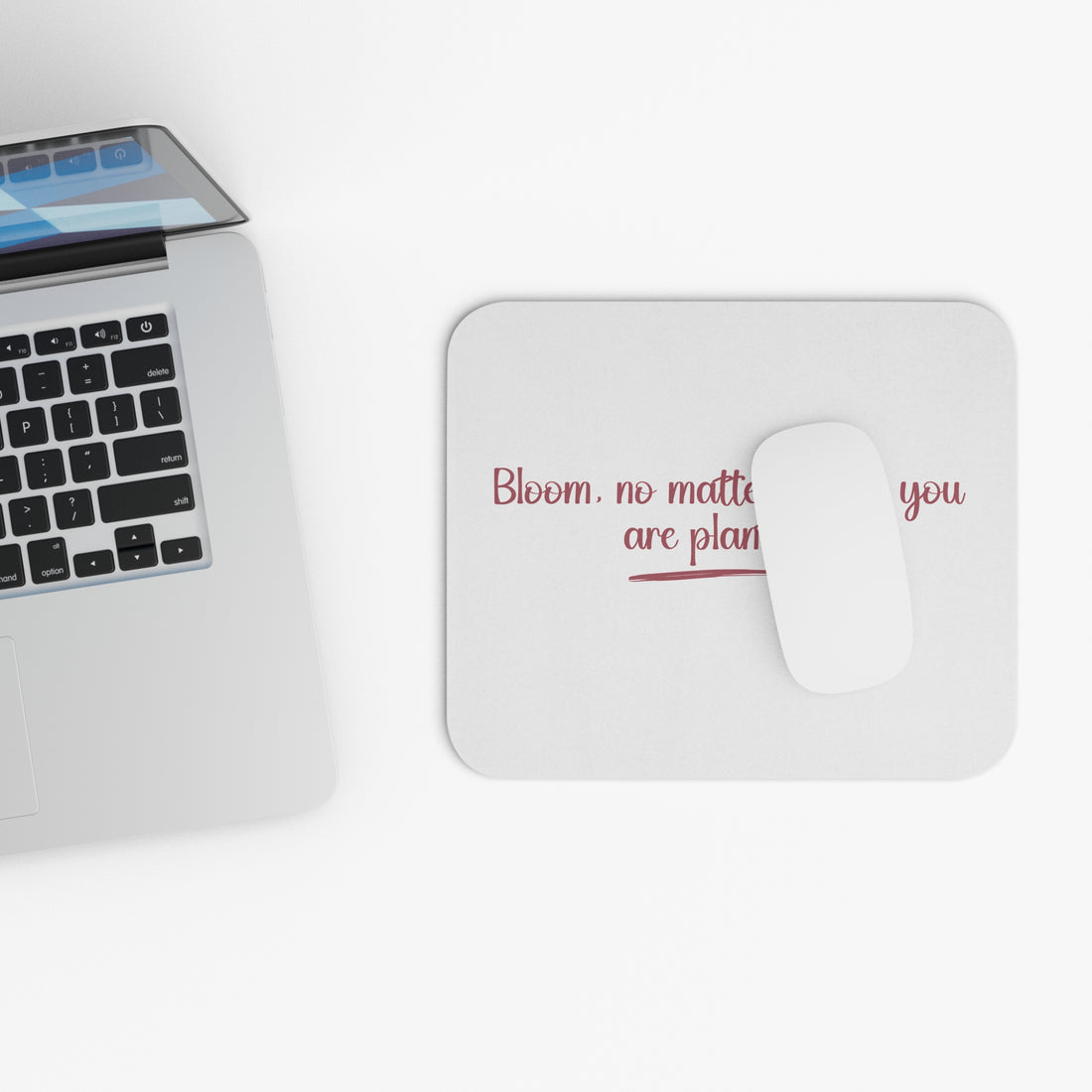 Mouse pad with motivational quote on a desk with a computer mouse, keyboard, and sunglasses.