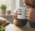 White mug with black handle and 'Daddy Gardener' text and garden illustration on a beige background