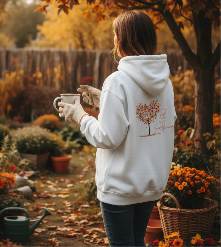 Person wearing a white hoodie with a tree design in an autumn garden.