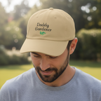 Man wearing a beige cap with 'Daddy Gardener' text in an outdoor setting