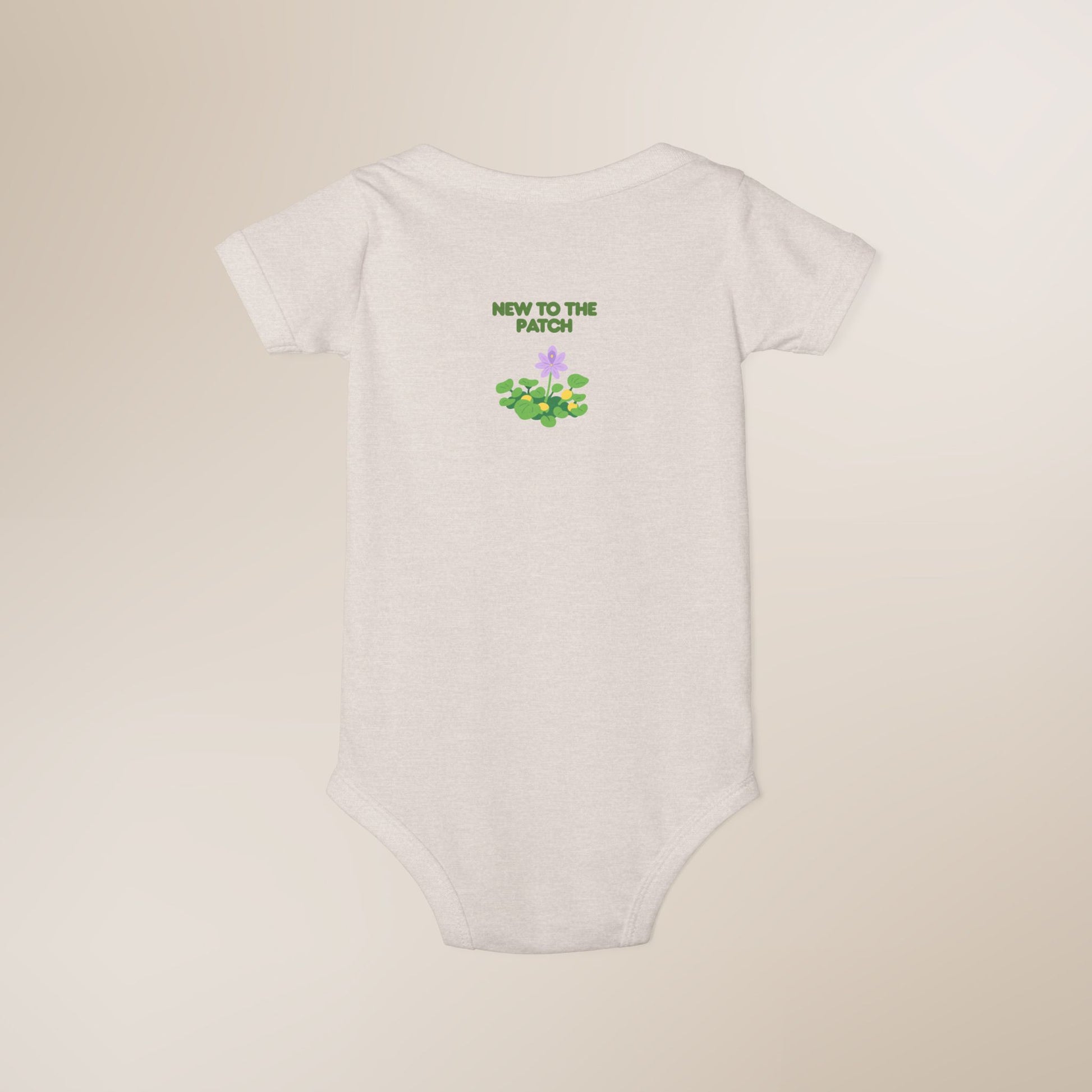 White baby onesie with 'New to the Patch' text and design on a beige background