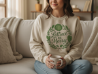 Person wearing a sweater with 'Lettuce Be Merry' design, holding a mug on a couch.
