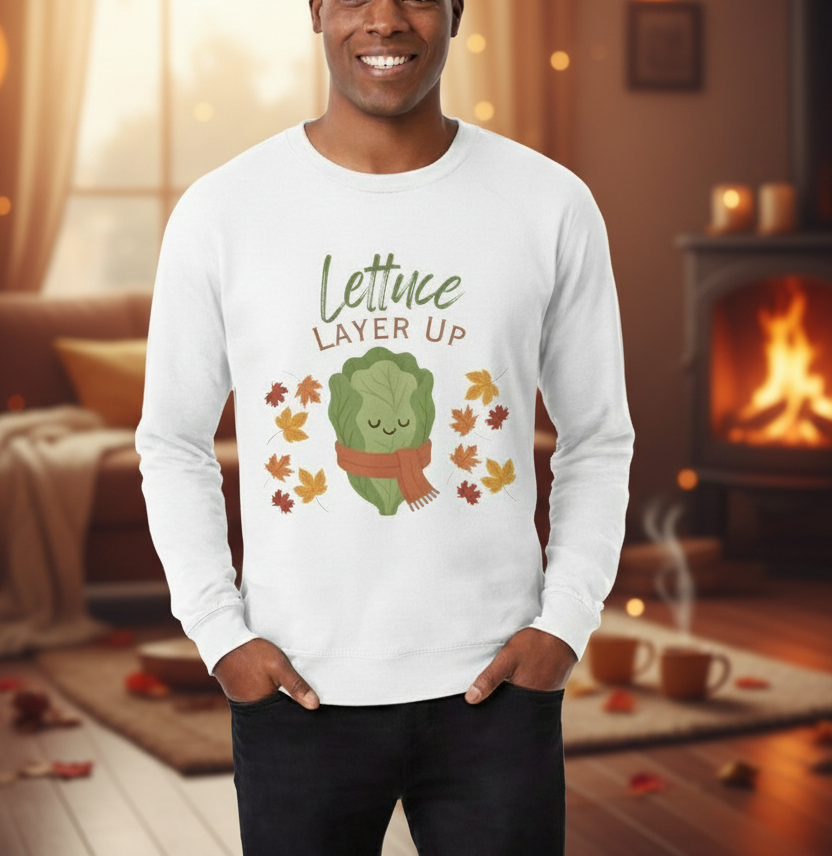 Person wearing a white long-sleeve shirt with a lettuce graphic and text in a cozy indoor setting.