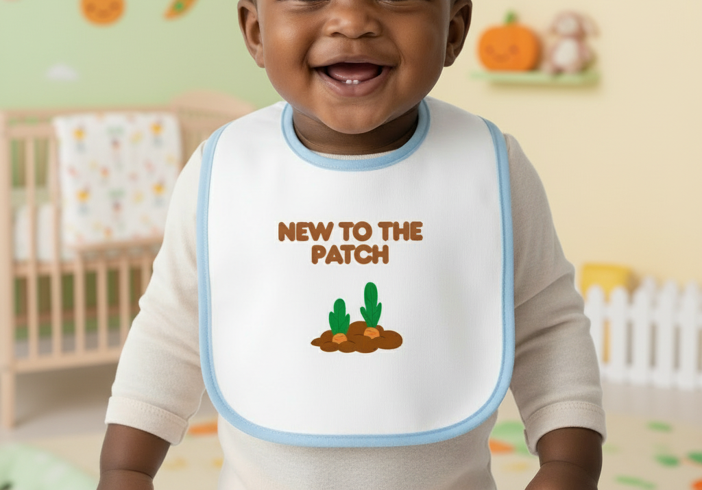 Child wearing a bib with 'New to the Patch' text and cactus illustration in a nursery setting.