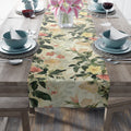 Floral table runner on a wooden table with place settings.