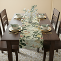 Dining table set with floral table runner, plates, and chairs in a room.