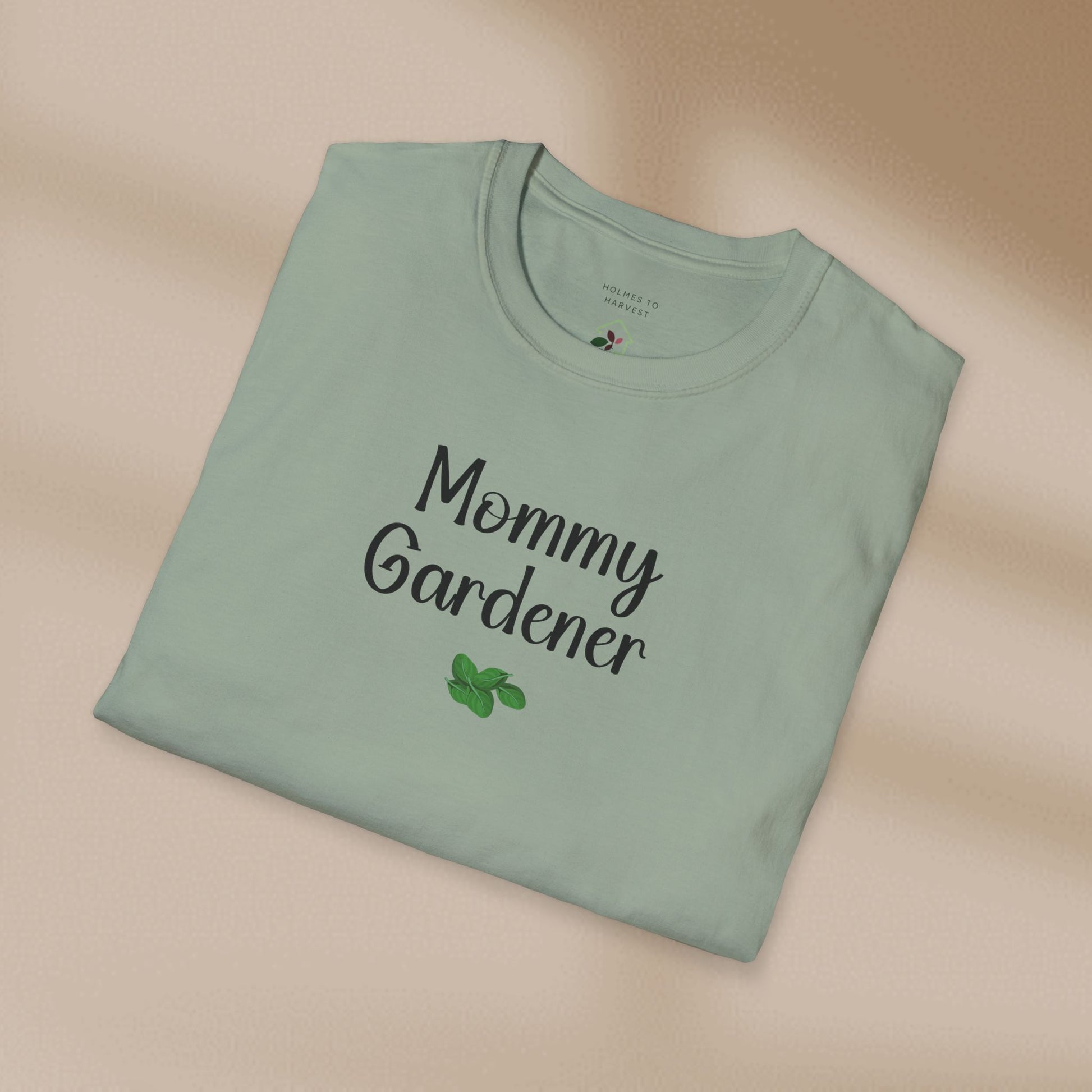 Folded green t-shirt with 'Mommy Gardener' text on a beige background