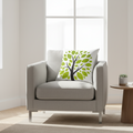 Gray armchair with a decorative pillow featuring a tree design in a bright room.