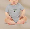 Baby wearing a gray onesie with 'Baby Bay Leaf' text and logo on a beige background