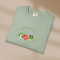 Folded light green t-shirt with gardening-themed design on a beige background