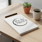 Notebook with 'Live & Garden' logo on a wooden table with a cup of coffee and plant.