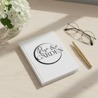 Notebook with 'Rise & Garden' on a wooden surface with glasses and pen